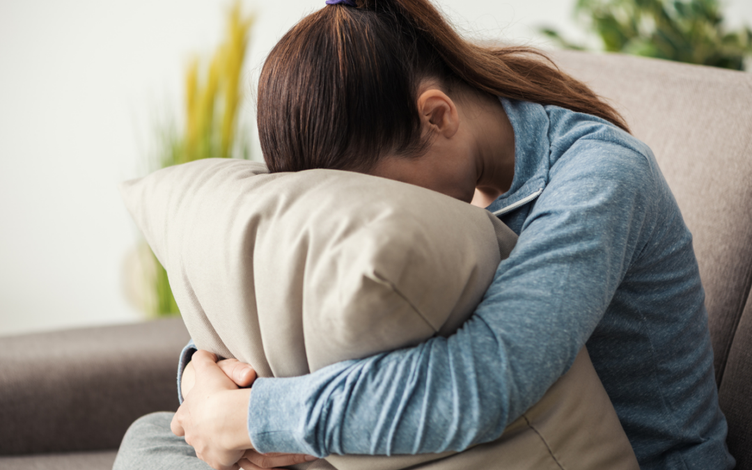Woman sitting on the couch with her head in the pillow